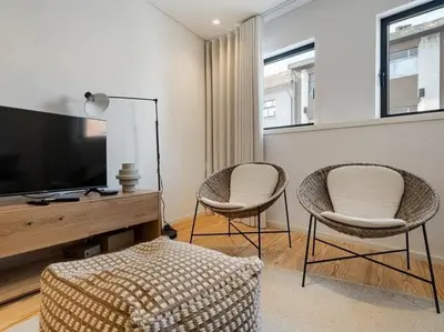 a living room with two chairs and a flat screen tv at Stylish Flat with Balcony, In Central Porto in Porto