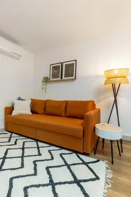an orange couch in a living room with a lamp at Modern 1BR Apartment - Brand New Bonjardim F in Porto