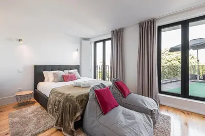a bedroom with a bed and a couch and windows at GuestReady - One Step Closer in Porto