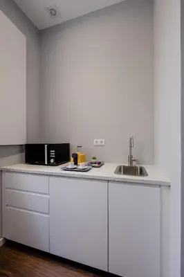 a white kitchen with a microwave and a sink at Plaza - Charming GuestHouse in Porto