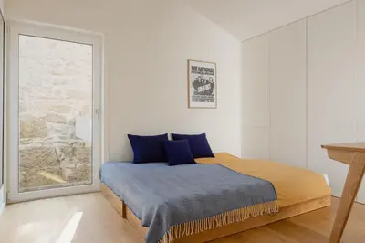 a bedroom with a bed with blue sheets and a window at Volta do Patio in Porto