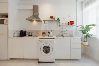 a white kitchen with a washing machine in it at Downtown Formosa Studio by Vacationy in Porto
