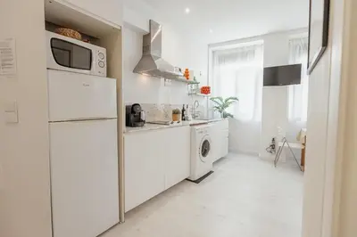 a white kitchen with a refrigerator and a washer and dryer at Downtown Formosa Studio by Vacationy in Porto