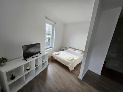 a white bedroom with a bed and a tv at Antas Place B in Porto