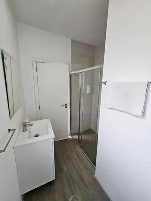 a white bathroom with a shower and a sink at Antas Place B in Porto
