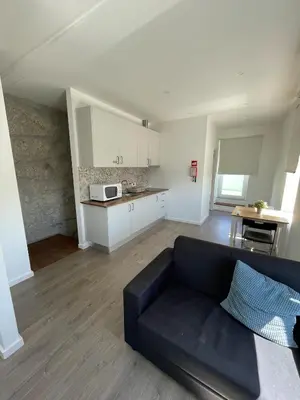 a living room with a black couch and a kitchen at Antas Place B in Porto