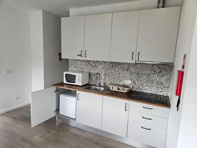 a white kitchen with white cabinets and a microwave at Antas Place B in Porto