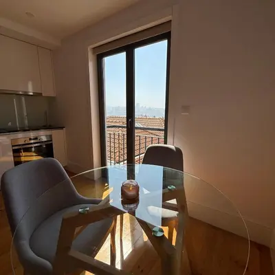 a kitchen with white cabinets and a living room at Flores Street Apartment - Porto City Center in Porto