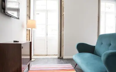 a living room with a blue couch and a television at Porto República Suites in Porto