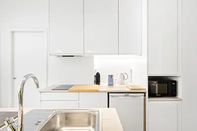 a white kitchen with white cabinets and a sink at GuestReady - Charming Studio in Porto Centre in Porto