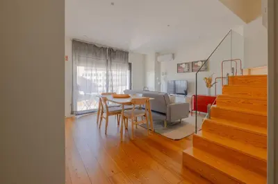 a dining room and living room with a table and stairs at Trindade Skyline Premium by Hosty in Porto