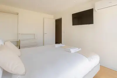 a white bedroom with a white bed and a television at Trindade Skyline Premium by Hosty in Porto