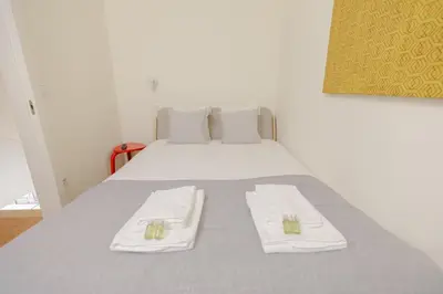 a bedroom with a bed with white sheets and towels at Trindade Skyline Premium by Hosty in Porto
