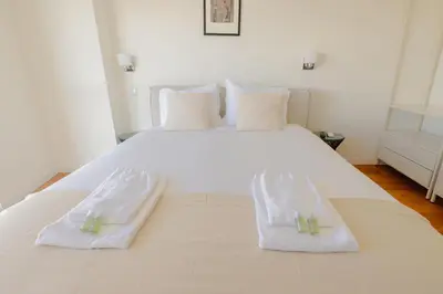 a large white bed with two towels on it at Trindade Skyline Premium by Hosty in Porto