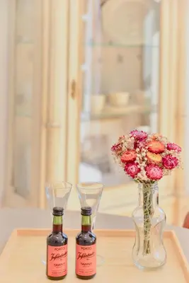 two bottles of wine and a vase with flowers at Studio Palazzo, Antique Charm with Romantic Balcony and AC in Porto