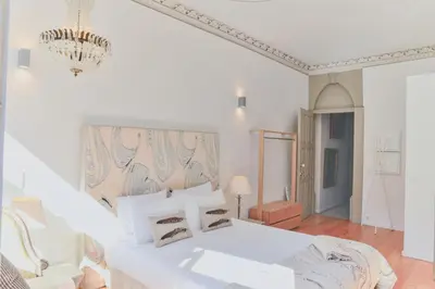 a white bedroom with a white bed and a chandelier at Studio Palazzo, Antique Charm with Romantic Balcony and AC in Porto