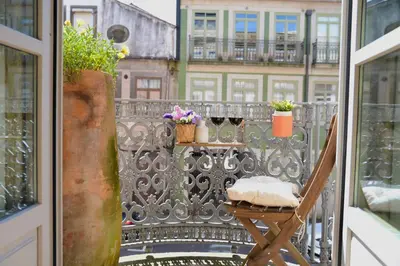 a balcony with a chair and a table with flowers at Studio Palazzo, Antique Charm with Romantic Balcony and AC in Porto