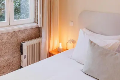a bedroom with a bed with white pillows and a window at Cozee Camões in Porto