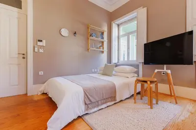 a bedroom with a bed and a flat screen tv at Cozee Camões in Porto