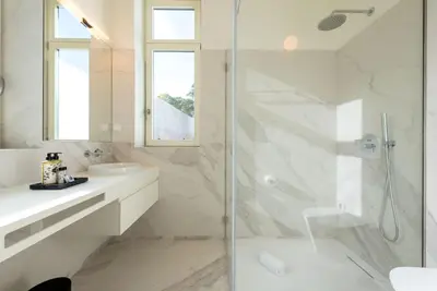 a white bathroom with a shower and a sink at Almada 559 - Eça Atelier by Lisbeyond in Porto