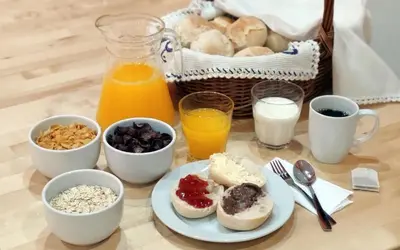 a table with a plate of breakfast foods and a basket of bread at Best Guest Porto Hostel in Porto