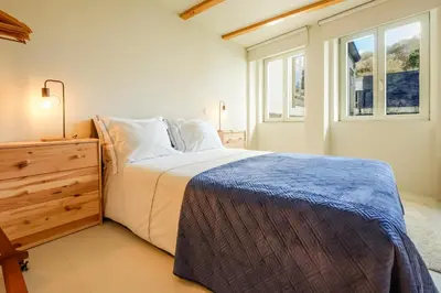 a bedroom with a bed and a dresser and windows at The Riverside House in Porto