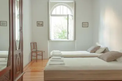 two beds in a white room with a window at Carolina M Apartment in front of Metro in Porto