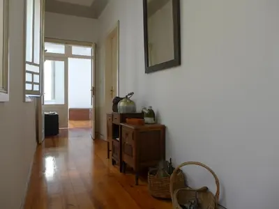 a room with a white wall and a wooden floor at Carolina M Apartment in front of Metro in Porto