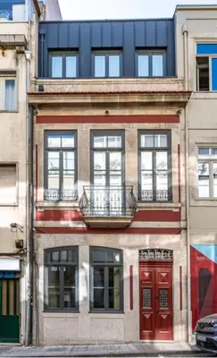 a building with red doors and windows on a city street at Bonjardim Suites in Porto