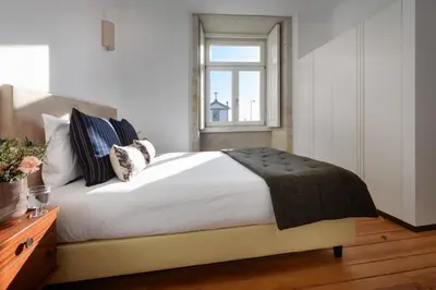 a bedroom with a large bed with a window at Condes de Azevedo Palace Apartments in Porto