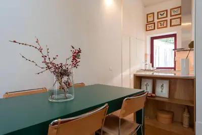 a kitchen with a green table with chairs and a vase with flowers at Riverfront Heritage House in Vila Nova de Gaia