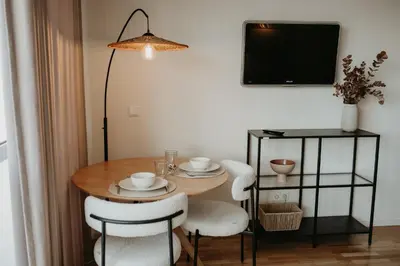 a dining room table with white chairs and a television at Bolhão Downtown in Porto