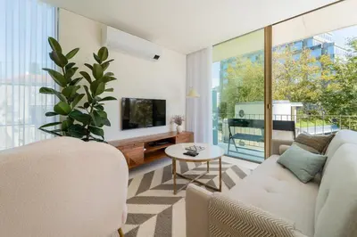 a living room with a white couch and a tv at The Luminous by Lovely Memories - Pool Access in Porto
