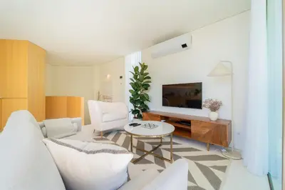 a living room with a white couch and a tv at The Luminous by Lovely Memories - Pool Access in Porto