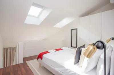 a white bedroom with a bed with white walls and a skylight at Liiiving in Porto - Luxury Gallery Apartment I in Porto