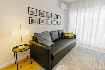 a black leather couch in a living room with a lamp at Cozy Bonfim by Hosty in Porto
