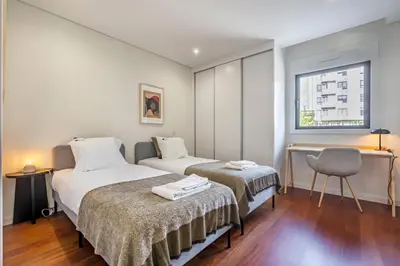 a bedroom with two beds and a chair and a window at Nomad's Lux - 2bdr & Parking Flores Square Porto in Porto