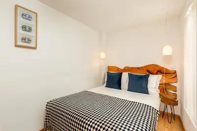a white bedroom with a bed with blue pillows at YOUROPO - Cosy in Porto