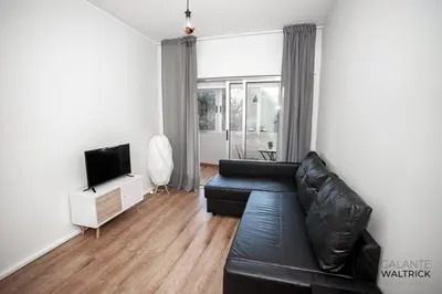 a living room with a black leather couch and a television at Quiet 3BR Flat - City Center - Warm and Bright - Remote Work in Porto