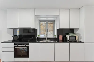a kitchen with white cabinets and a black appliances at GuestReady - enjoy the Best of Porto in Porto