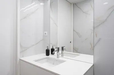 a white bathroom with a sink and a mirror at GuestReady - enjoy the Best of Porto in Porto