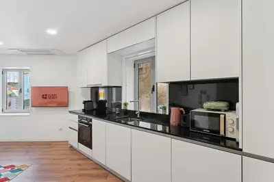 a kitchen with white cabinets and black counter tops at GuestReady - enjoy the Best of Porto in Porto