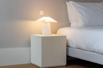 a white lamp sitting on a table next to a bed at Entreparedes House in Porto