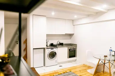 a white kitchen with a washing machine in it at Magnificent Cais de Gaia Duplex in Vila Nova de Gaia