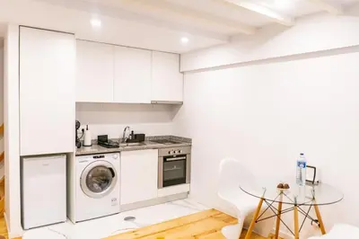 a kitchen with white cabinets and a washer and dryer at Magnificent Cais de Gaia Duplex in Vila Nova de Gaia