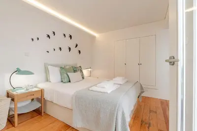 a white bedroom with a bed with birds on the wall at City Center Lello and Clerigos 5min Walk with Free Parking in Porto