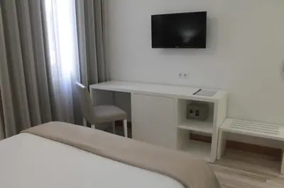 a room with a bed and a desk with a television at Seculo Soft in Porto