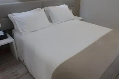 a bed with white sheets and pillows in a room at Seculo Soft in Porto