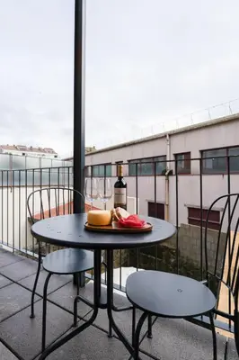 a table with a plate of food on a balcony at Bonfim Charming Flats by HostWise in Porto