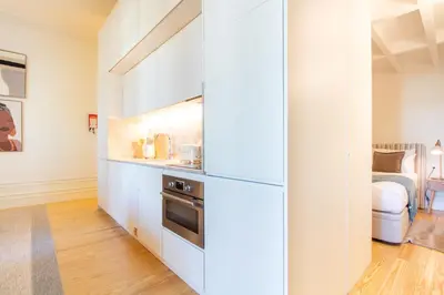 a kitchen with white cabinets and a bed in a room at Deluxe Design 1BR w Terrace by LovelyStay in Porto